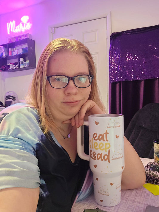 Marie Gems founder sitting in her home office holding a custom book lover tumbler while sharing her online business journey and entrepreneurship story.