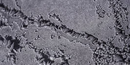 Close-up of frost patterns on a dark surface