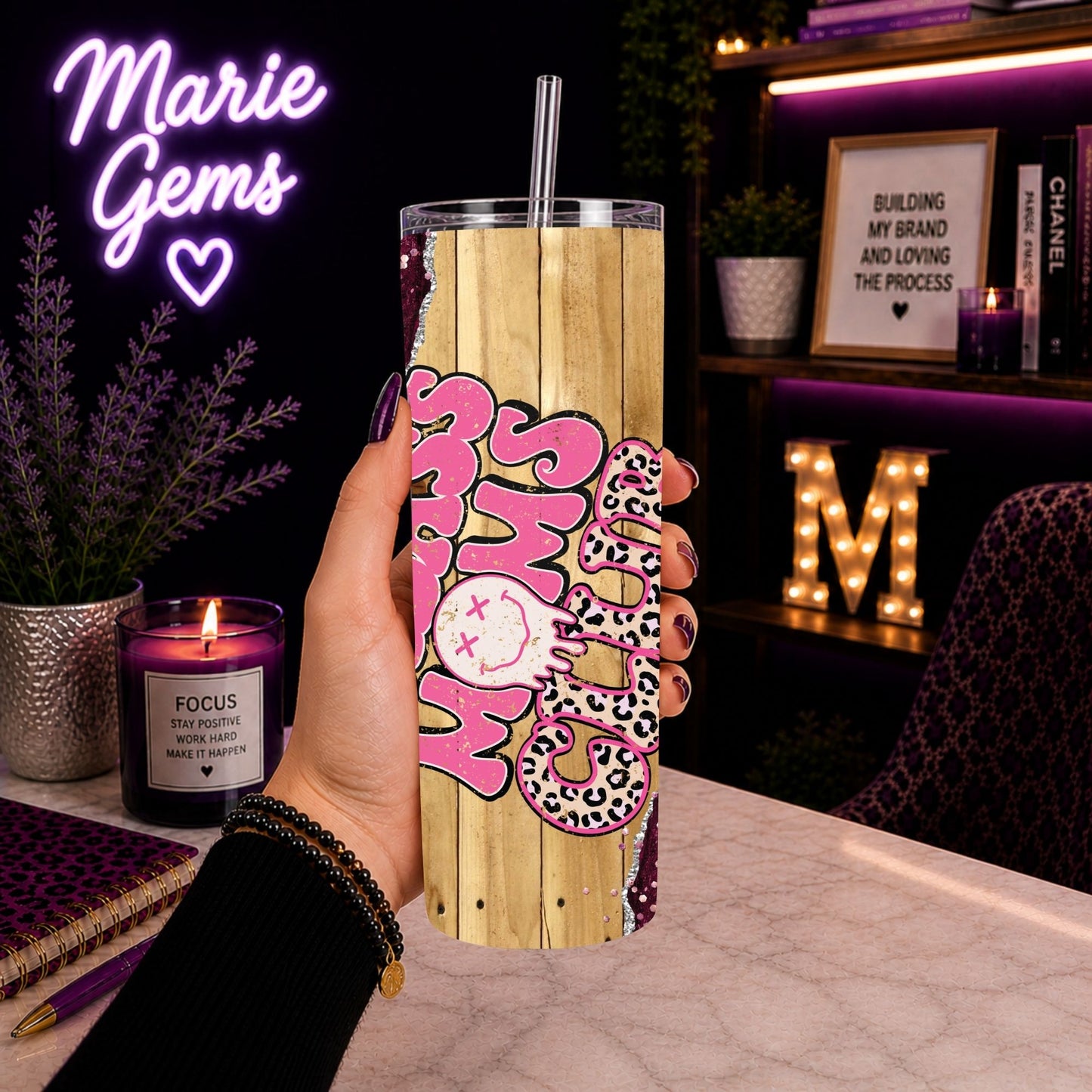 Hand holding Badass Moms Club Tumbler 20 Oz Pink Glitter Leopard Floral Skinny Cup Gift Mom Life Coffee Cup in cozy desk setting