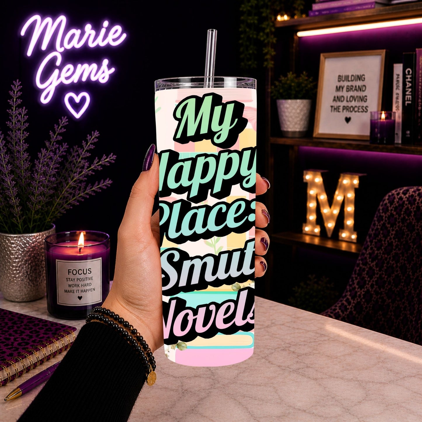 Hand holding Smut Novel Tumbler | My Happy Place Spicy Reader Cup with cozy desk setup and purple lighting background