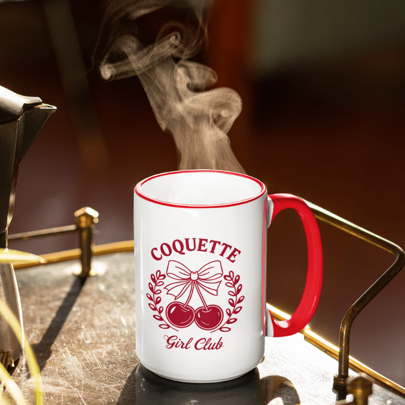 Aesthetic Cherry Coquette Coffee Mug with red handle and cherry bow design steaming on a table.