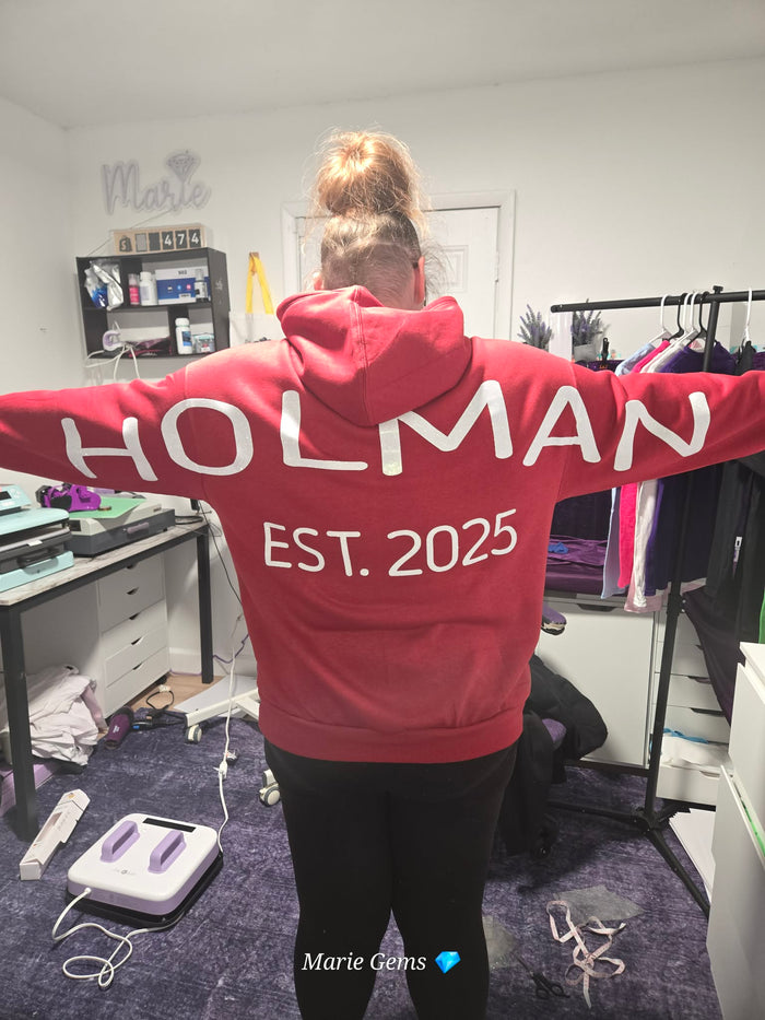 Customer Rochelle wearing a personalized Holman Est. 2025 hoodie inside the Marie Gems office showcasing custom apparel and handmade hoodie printing