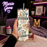 In My Art Student Era 20 oz Stainless Steel Tumbler showing bold varsity-inspired lettering surrounded by watercolor palettes, paint brushes, pencils, rulers, sketchbooks, and