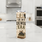 In My Bookworm Era Handmade 20 oz Stainless Steel Tumbler showing charming vintage-inspired artwork including stacked books, library cards, coffee mugs, bows, daisies, bookmarks