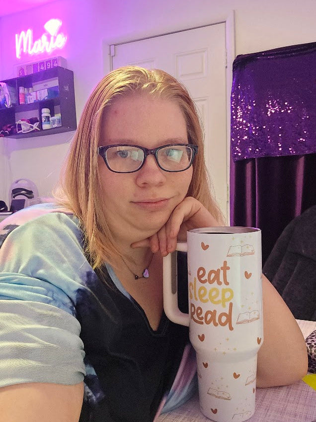Marie Gems founder in her purple-themed workspace and reading nook, helping small business owners with branding, website design, and Pinterest marketing.