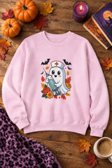 Nurse Ghost Halloween crewneck sweatshirt in light pink with cute nurse ghost graphic, styled flat lay with pumpkins, a purple candle, books and a stethoscope