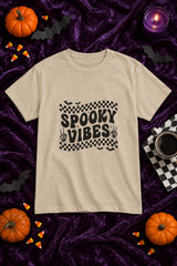 Spooky Vibes Retro Checkerboard t-shirt in sand with checkerboard Spooky Vibes graphic, styled flat lay with pumpkins, candy corn, bats and a purple candle