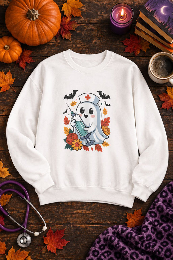 Nurse Ghost Halloween crewneck sweatshirt in white with cute nurse ghost graphic, styled flat lay with pumpkins, a purple candle, books and a stethoscope