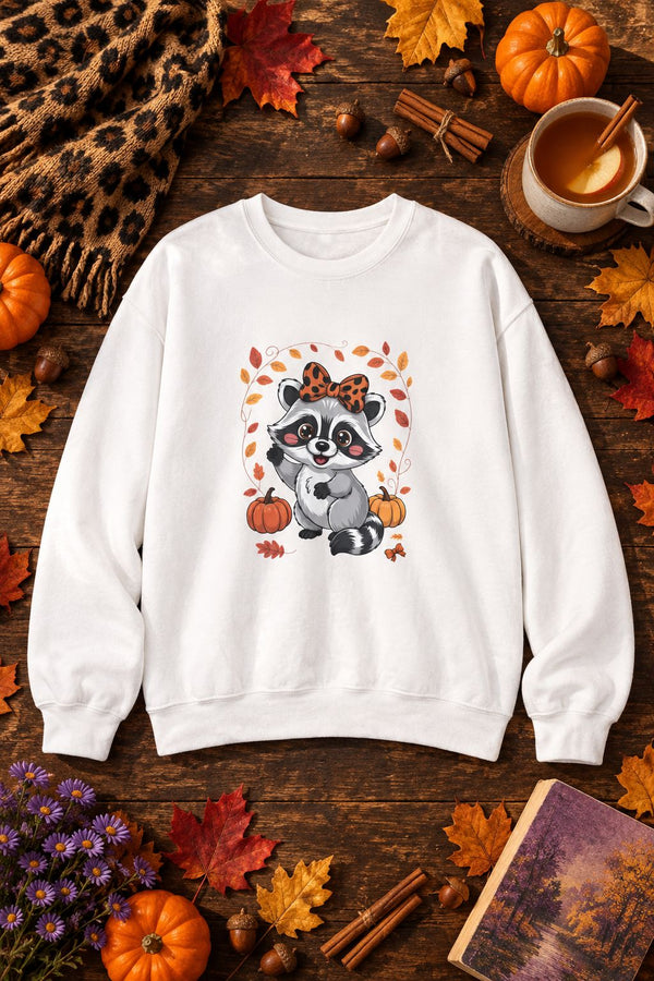 Cute Fall Raccoon crewneck sweatshirt in white with leopard bow raccoon graphic, styled flat lay with pumpkins, maple leaves, cinnamon sticks and a cheetah print scarf