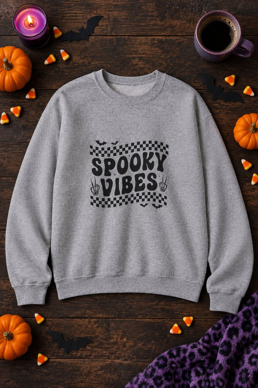 Spooky Vibes Retro Checkerboard crewneck sweatshirt in sport grey with checkerboard Spooky Vibes graphic, styled flat lay with pumpkins, candy corn, bats and a purple candle