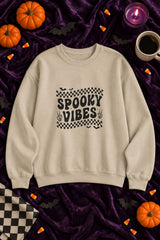 Spooky Vibes Retro Checkerboard crewneck sweatshirt in sand with checkerboard Spooky Vibes graphic, styled flat lay with pumpkins, candy corn, bats and a purple candle