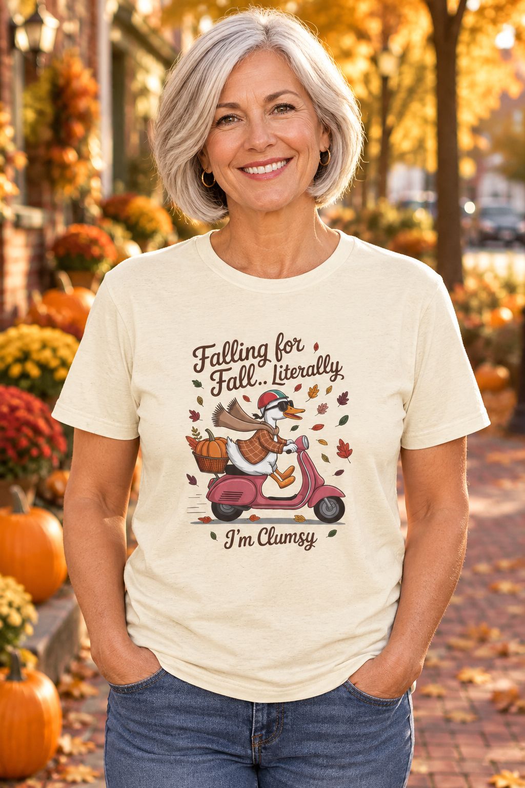 Person wearing the Falling for Fall Literally I'm Clumsy t-shirt in natural with goose on a scooter graphic in a fall setting