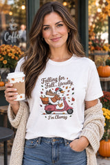 Person wearing the Falling for Fall Literally I'm Clumsy t-shirt in white with goose on a scooter graphic in a fall setting