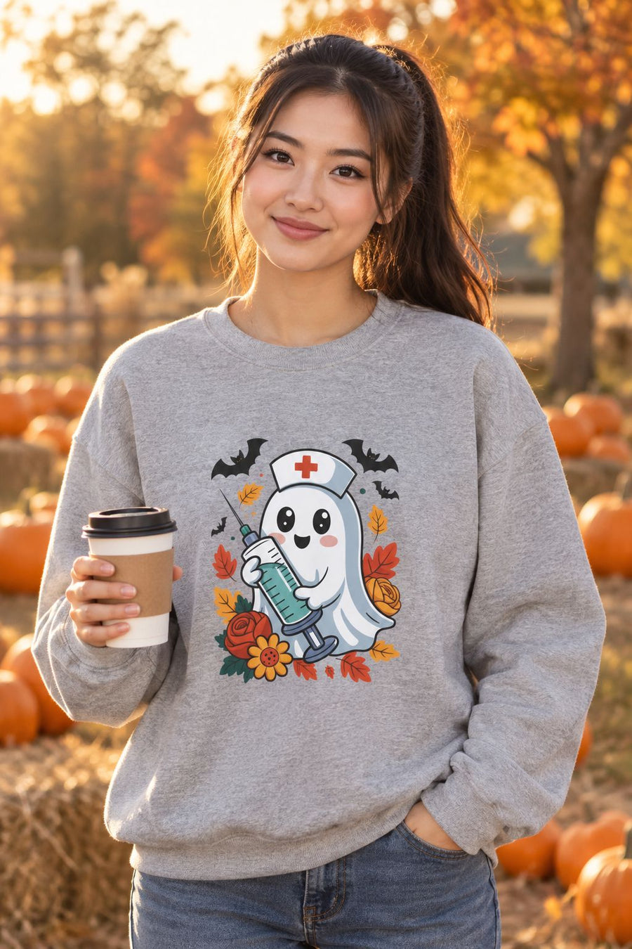 Person wearing the Nurse Ghost Halloween crewneck sweatshirt in sport grey with cute nurse ghost graphic in a fall setting