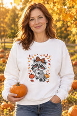 Person wearing the Cute Fall Raccoon crewneck sweatshirt in white with leopard bow raccoon graphic in a fall setting