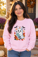 Person wearing the Nurse Ghost Halloween crewneck sweatshirt in light pink with cute nurse ghost graphic in a fall setting
