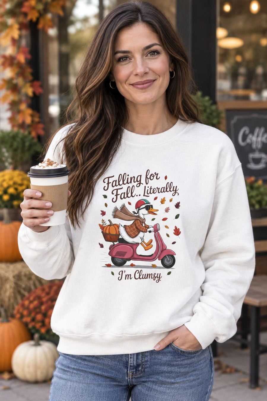 Person wearing the Falling for Fall Literally I'm Clumsy crewneck sweatshirt in white with goose on a scooter graphic in a fall setting