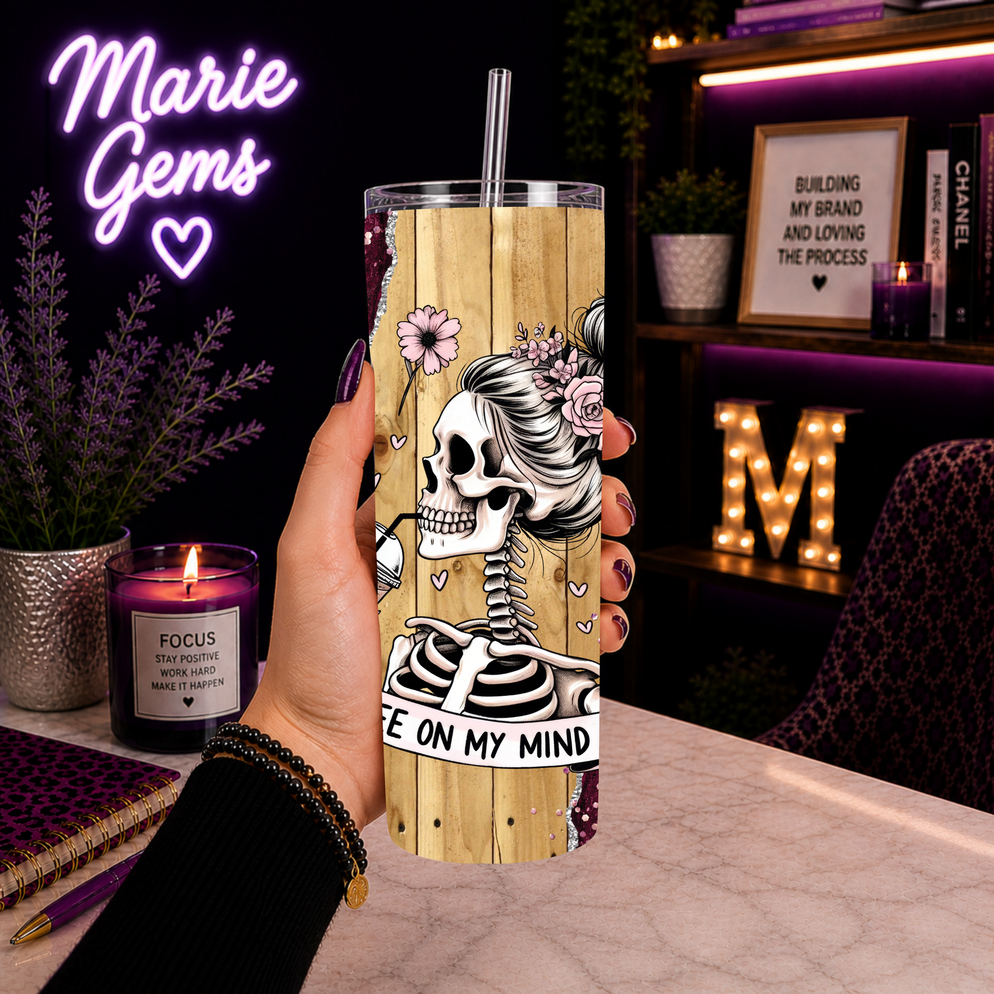 Goth Glam Skeleton Coffee Tumbler 20 Oz With Pink Glitter Roses Insulated Skinny Cup For Iced Drinks Gift For Her held in hand by desk with cozy decor.