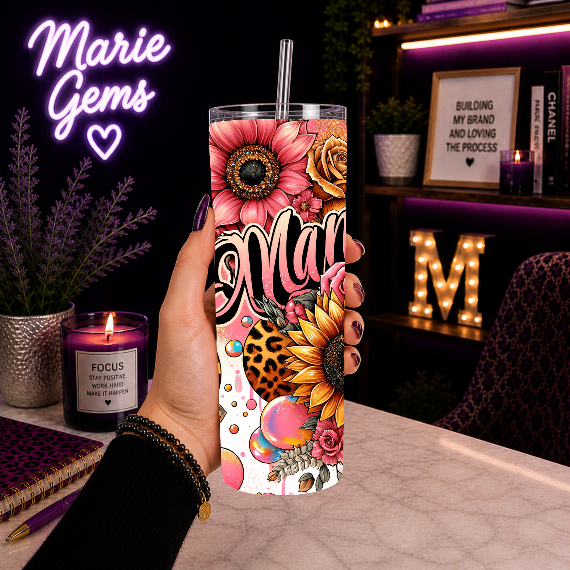 Hand holding Mama Tumbler 20 Oz Leopard Sunflower Pink Floral Skinny Stainless Steel Tumbler With Lid And Straw in cozy purple-lit desk setting.