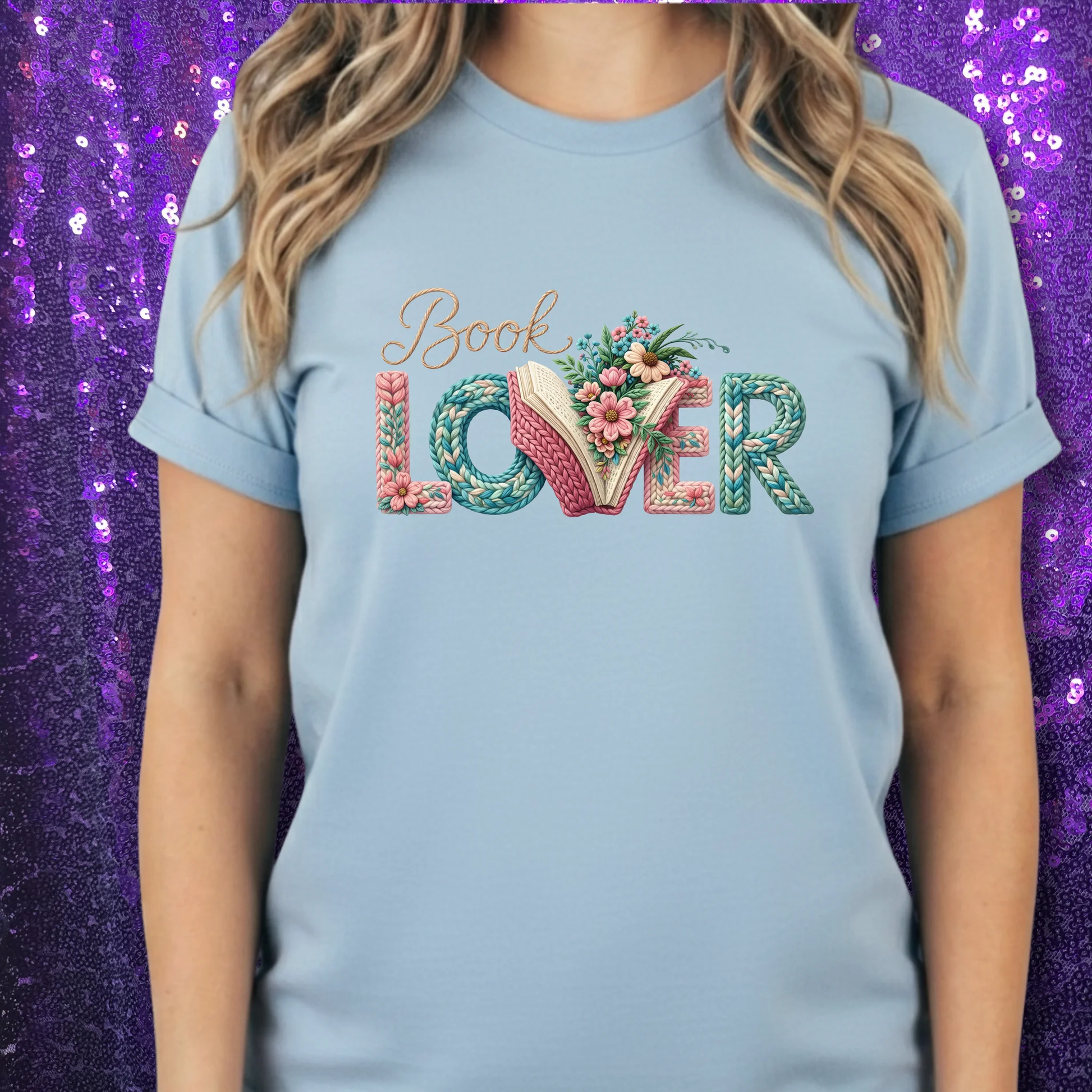 Light blue cotton tee featuring floral 'Book Lover' typography; an open book forms the word LOvER.